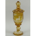 A Bohemian amber stained goblet and cover, engraved with two deer in a forest, supported on a lobed ... 