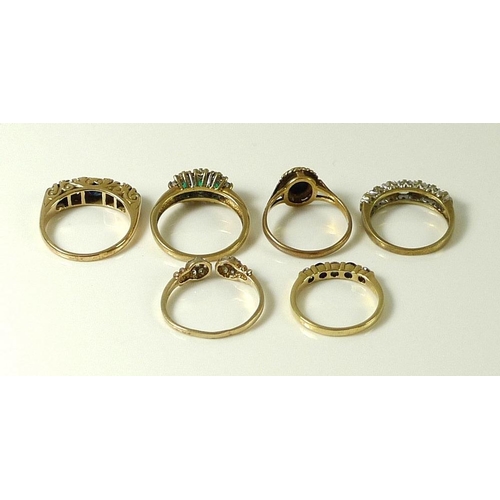 828 - A group of six 9ct gold rings, comprising a ring set with three emeralds surrounded by diamonds, ree... 