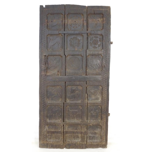 940 - A Moorish carved wooden door, possibly 17th century, carved with eighteen panels of animal and flora... 