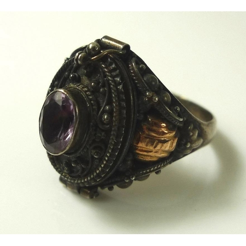 811 - An early 20th century silver poison ring, the hinged lid set with oval amethyst, applied bead and fo... 