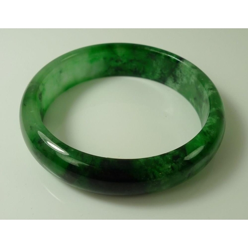 825 - An apple and spinach jade bangle, modern, 7.2cm diameter, 53.7g.