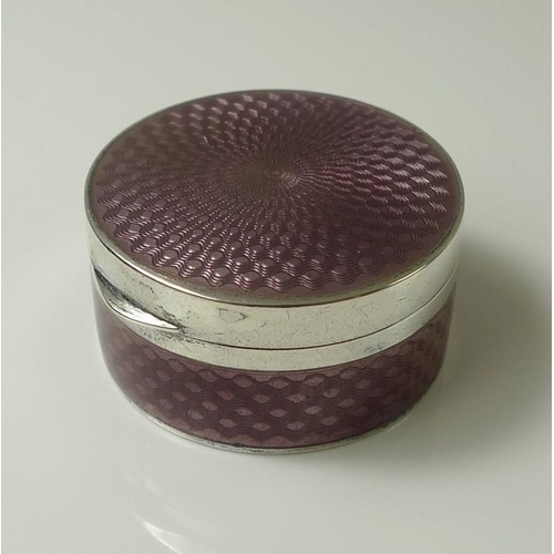 828 - A silver and pink guilloche enamel cylindrical pill box with engine turned detailing and having an e... 