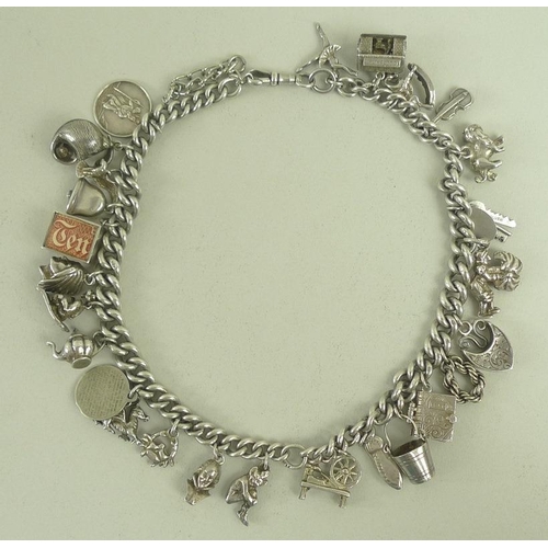 831 - A silver charm bracelet with twenty six charms including a rocking horse, lion, shell, bust of Shake... 