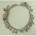 A silver charm bracelet with twenty six charms including a rocking horse, lion, shell, bust of Shake... 