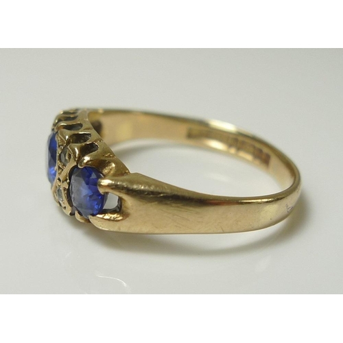 838 - A 9ct gold dress ring, set with three cornflower blue stones, likely sapphires and interspersed with... 