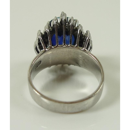 849 - An 18ct white gold, diamond and sapphire dress ring, the central oval royal blue stone of 10 by 12mm... 