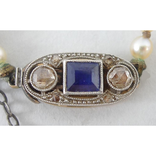 850 - A seed pearl single strand necklace, the clasp of Art Deco design and set with an emerald cut sapphi... 