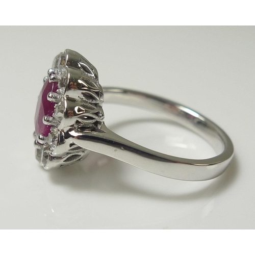 858 - An 18ct white gold, diamond and ruby dress ring, the oval cut ruby of approximately 8.2 by 5.8mm, su... 