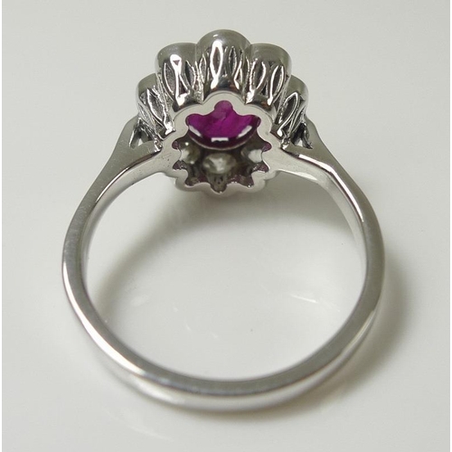 858 - An 18ct white gold, diamond and ruby dress ring, the oval cut ruby of approximately 8.2 by 5.8mm, su... 