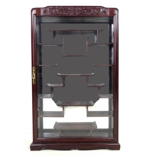 867 - A modern Chinese hardwood display cabinet, carved with opposing dragons, glazed door and mirror back... 