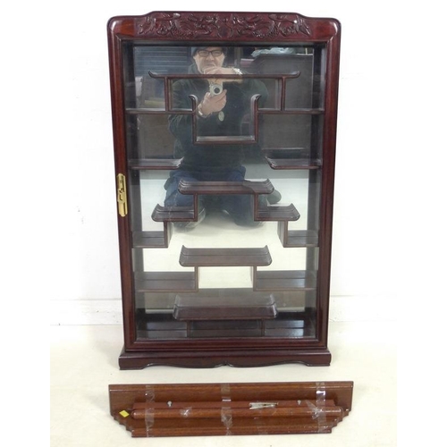 867 - A modern Chinese hardwood display cabinet, carved with opposing dragons, glazed door and mirror back... 