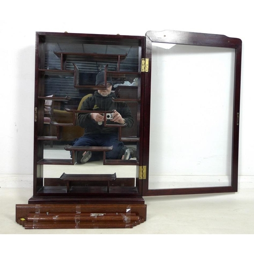 867 - A modern Chinese hardwood display cabinet, carved with opposing dragons, glazed door and mirror back... 