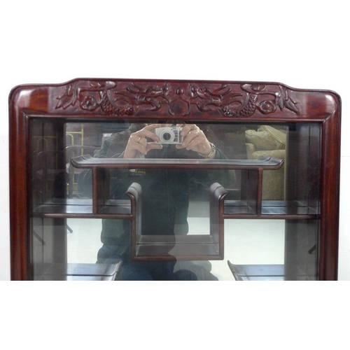 867 - A modern Chinese hardwood display cabinet, carved with opposing dragons, glazed door and mirror back... 