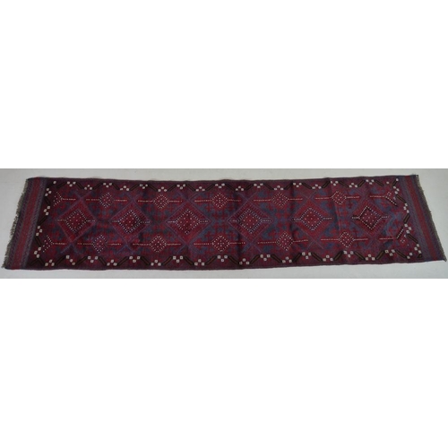 873 - A Meshwani runner rug, with dark red and dark blue ground, six diamond pendants, further cream decor... 