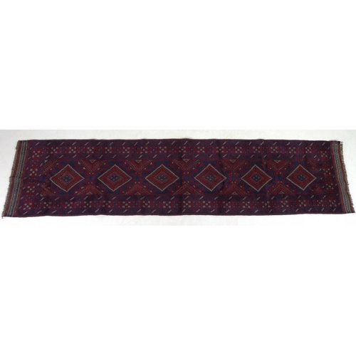 877 - A Meshwani runner rug, with dark red and dark blue ground, six diamond pendants, further cream decor... 