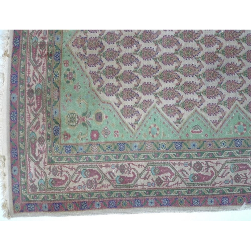 949 - A Persian wool rug, with cream ground, multiple boteh to the field, pale green edges and floral moti... 