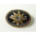 A garnet and diamond brooch, the ovoid garnet with a central starburst setting to a diamond of appro... 