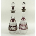 A near pair of mulberry flashed and cut glass decanters, the necks slice cut and bands to the body d... 