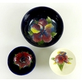 A group of three Moorcroft pottery bowls, all floral decorated, comprising the largest painted with ... 