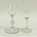 An 18th century wine glass with unusual knopped stem containing decorative air bubbles, raised on wi... 