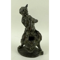 A late 19th century terracotta figurine modelled as a faun playing pan pipes and sitting on a large ... 