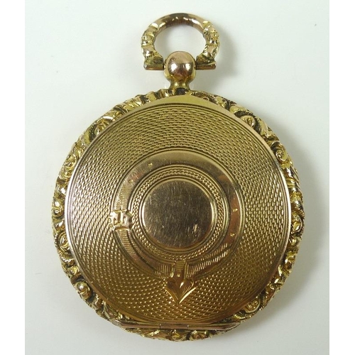 805 - A Victorian yellow metal locket, the front and back engine turned with scroll cast rim, and suspensi... 