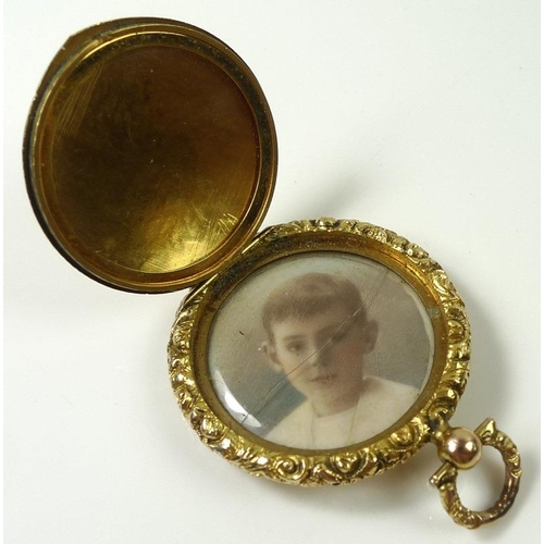 805 - A Victorian yellow metal locket, the front and back engine turned with scroll cast rim, and suspensi... 