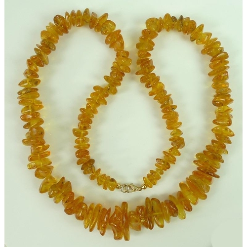 816 - A honey amber necklace, possibly Baltic, the amber pieces of graduating size, gold coloured metal cl... 