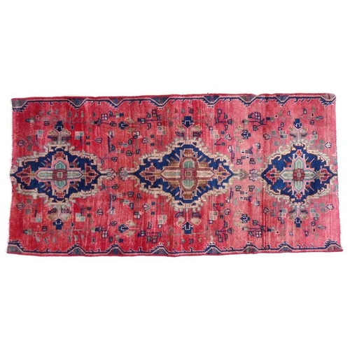 853 - A Hamadan rug with red ground and three blue medallions, 167 by 83cm.