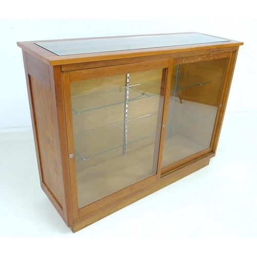 920 - An early 20th century Australian pine shop display cabinet, with two sliding glass doors, two full w... 