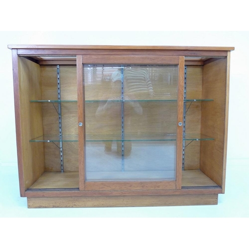 920 - An early 20th century Australian pine shop display cabinet, with two sliding glass doors, two full w... 