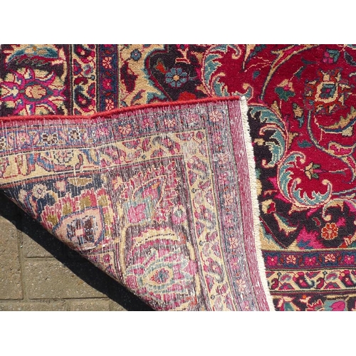 921 - A Meshed rug with dark red ground, cream and black foliate decoration, 308 by 212cm.