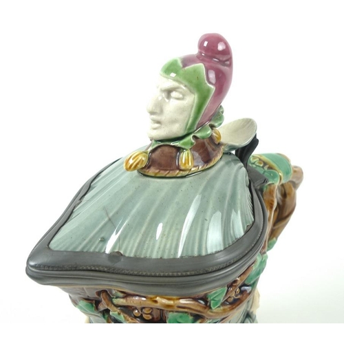 502 - A Minton Majolica lidded jug, the shell moulded lid with jester's head finial, Britannia metal mount... 