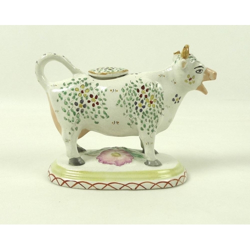 527 - A Staffordshire pottery cow creamer, late 19th century, with painted floral decoration, on an oval b... 