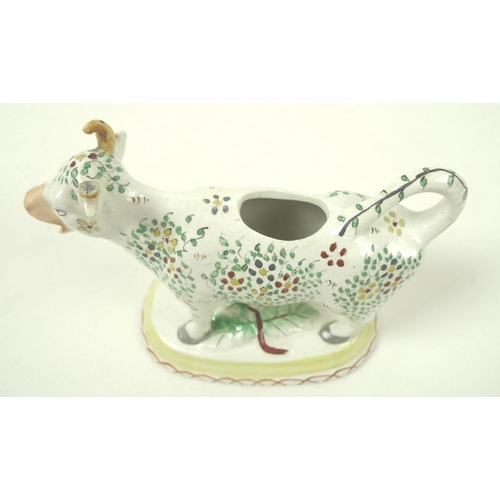 527 - A Staffordshire pottery cow creamer, late 19th century, with painted floral decoration, on an oval b... 