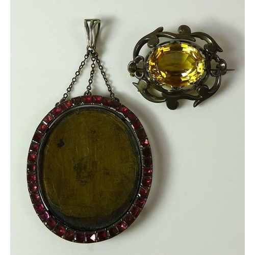 793 - An open faced oval pendant bordered with pave set rubies, together with a citrine brooch, in a white... 