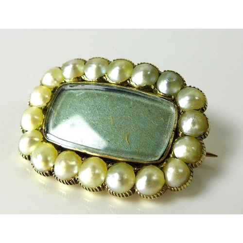 795 - A Regency mourning brooch, yellow metal, with eighteen half pearls set around a central insert, engr... 