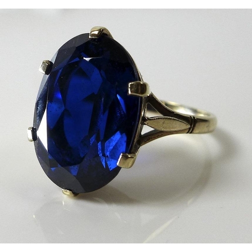 813 - A 9ct gold ring set with large oval cut blue stone, pierced claw setting and stylised leaf detailing... 