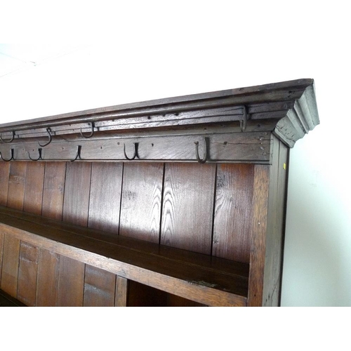 950 - An 18th century oak dresser with plate rack, the moulded cornice with iron cup hooks, the base with ... 