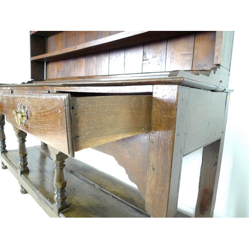 950 - An 18th century oak dresser with plate rack, the moulded cornice with iron cup hooks, the base with ... 