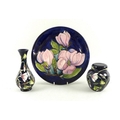 A Moorcroft wall plate decorated in the Magnolia design, diameter 26cm, together with a Moorcroft  v... 