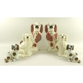 A group of Staffordshire flatback figurines modelled as spaniels, comprising a pair decorated in che... 