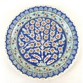 A Turkish pottery plate, decorated with a flower bush against a blue ground, two borders to edge, pa... 