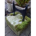 A cast metal boot scraper, black painted and set into a stone block.