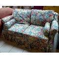A two seater sofa bed with floral covers.