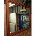 A modern wall mirror with rectangular plate, in a stained pine frame.