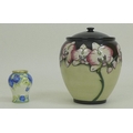 A modern Moorcroft vase and cover, the body depicting cream and pink orchids on cream and black grou... 
