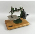 A Grain miniature toy sewing machine with green metal body, on wooden base, 18cm high, with original... 