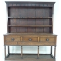 A George III oak dresser, with two shelf plate rack, original metal hooks, three frieze drawers with... 