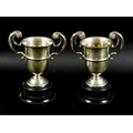 A pair of silver twin handled golf trophies, flying scroll handles to knopped urnular bodies, with i... 